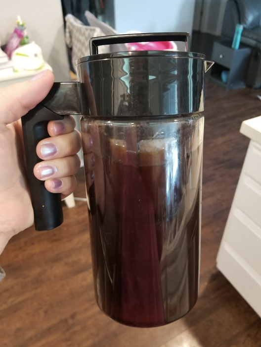 reviewer holding a tall mug filled with cold brew