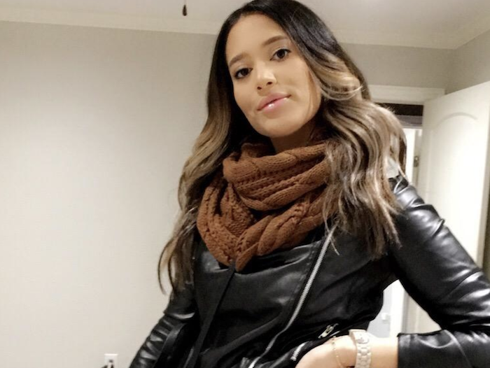 another reviewer wearing a brown scarf paired with a leather moto jacket