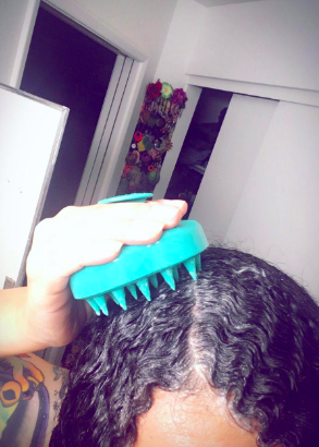 reviewer using the brush to massage their scalp