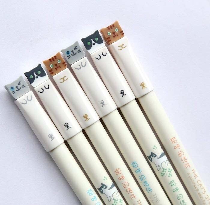 A set of six pens, each featuring a cat face on the top and paws along the body.