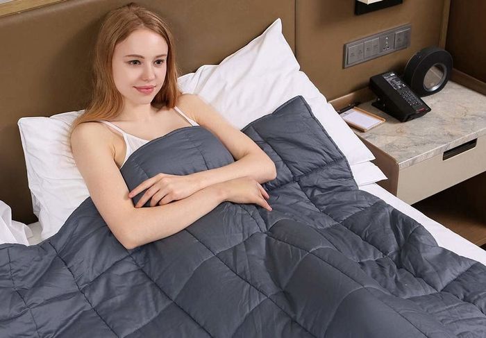 A person curled up in bed, enjoying the warmth and soothing comfort of a weighted blanket.