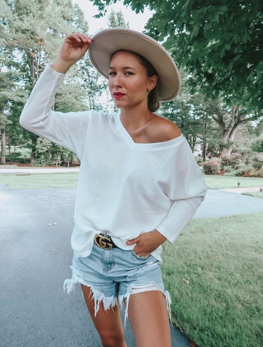 A reviewer styling the sweater in classic white, showing off its off-the-shoulder design.