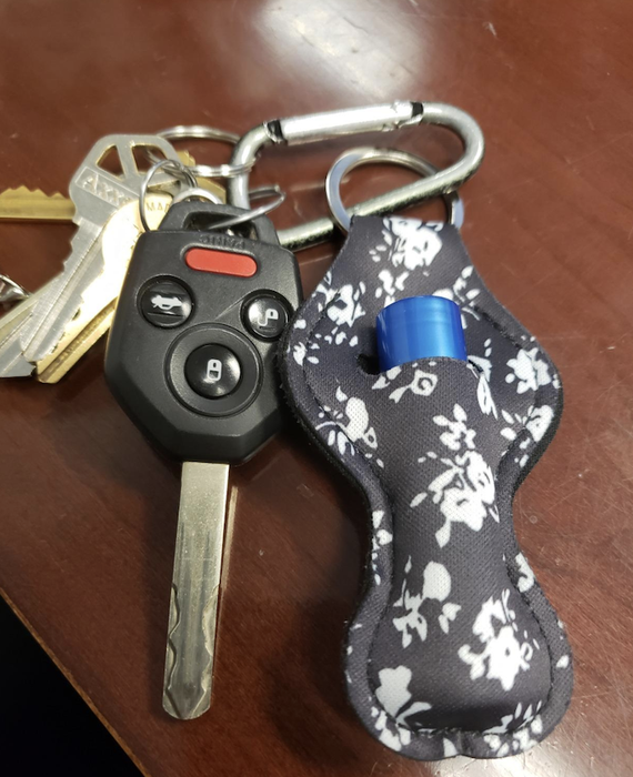 A close-up of the lip balm holder hanging on a keychain, surrounded by several keys.