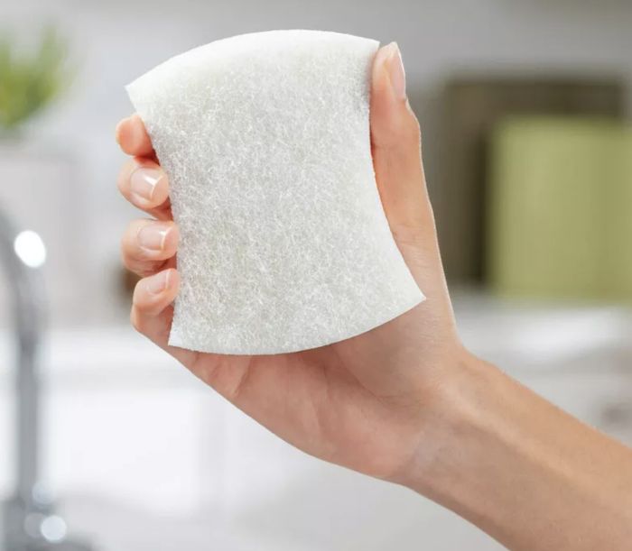 A hand gripping a white scrubber.