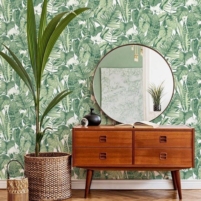 The tropical peel-and-stick wallpaper, paired with a console table and a plant.