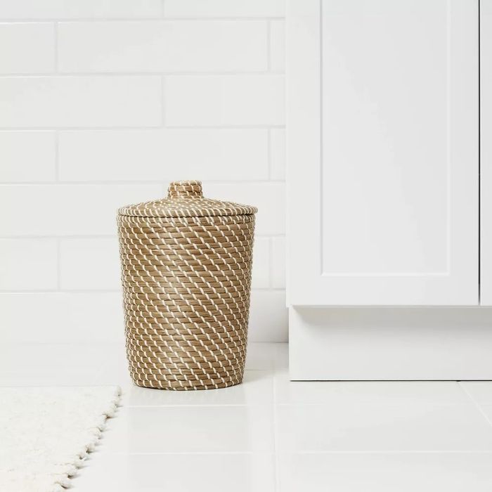 A woven wastebasket placed in a bathroom setting.