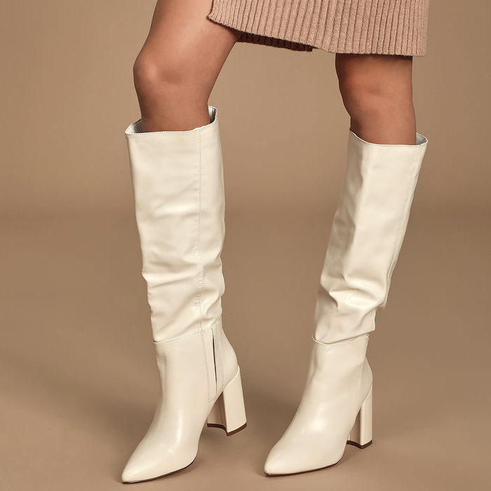 A model wearing the knee-high boots in off-white.