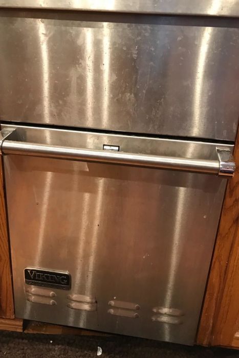 A reviewer’s photo of a stainless steel dishwasher covered in marks and smudges.