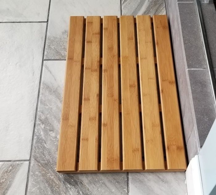 A photo showing the slatted bamboo mat placed on the bathroom floor.