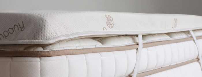 A mattress topper placed on top of a mattress, secured with straps.
