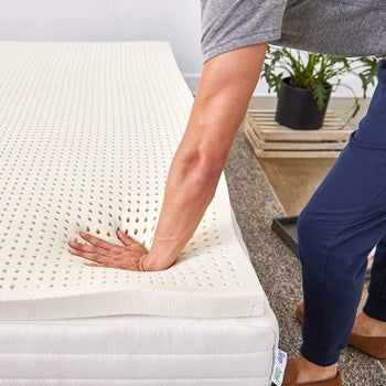 Model pressing hand into the topper to demonstrate its firmness, showing no lingering hand print