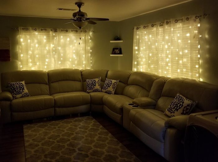 A review image showing string lights draped behind sheer curtains in a softly lit living room.