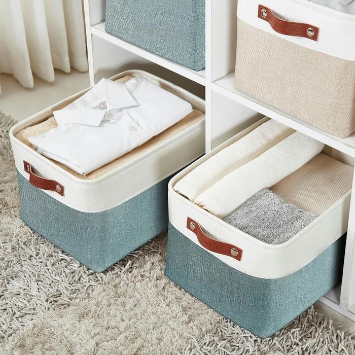 A set of stylish storage baskets neatly organized on shelves, each holding folded clothes and textiles, perfect for home organization.