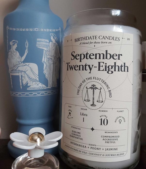 Mytourer's candle in a jar with the inscription 'September twenty-eighth, the day of the fluttering candle,' adorned with small astrological symbols for that date.