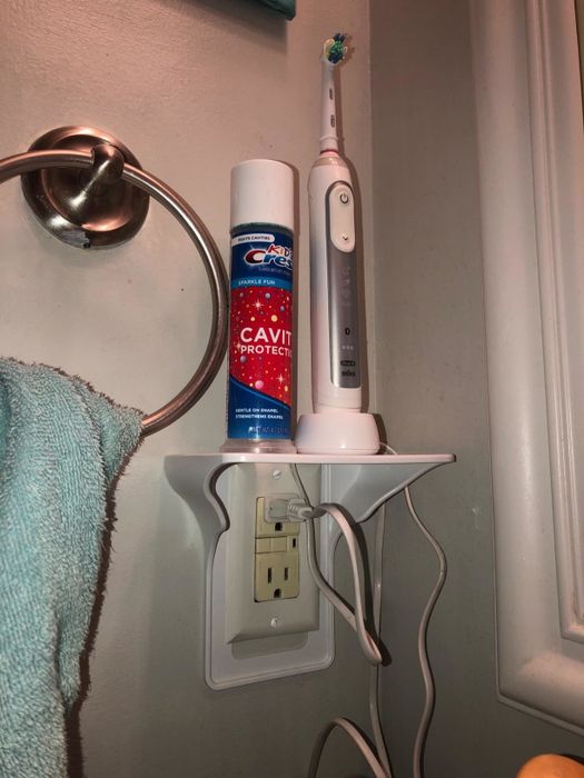 reviewer photo of an outlet shelf with an electric toothbrush and toothpaste neatly stored on it
