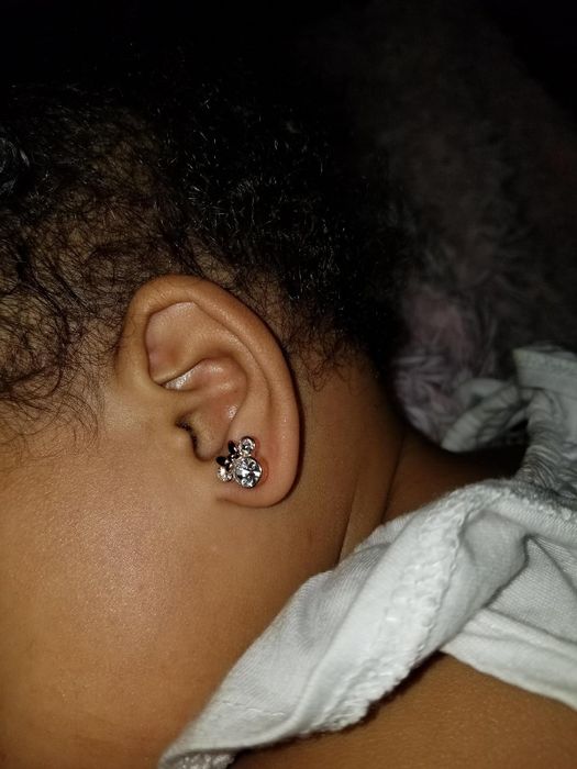 a child sporting silver Minnie Mouse-shaped earrings