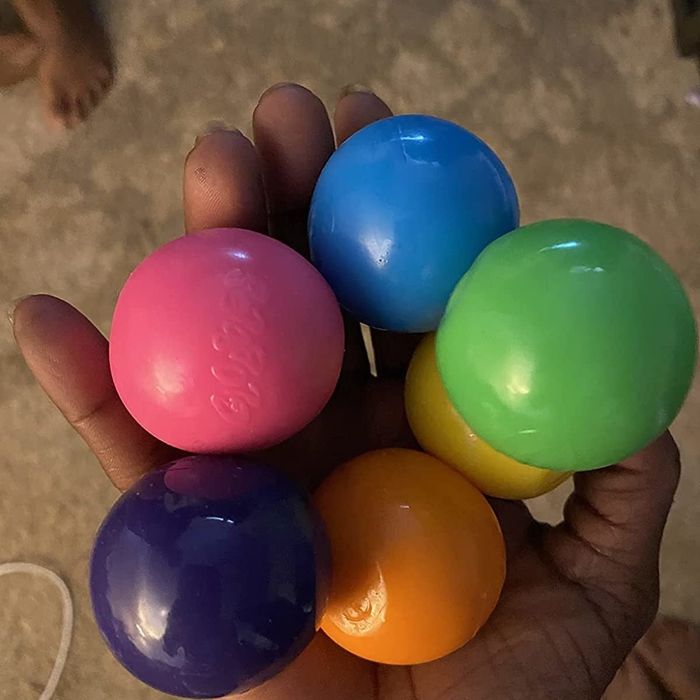 A reviewer holding the balls in shades of pink, purple, orange, yellow, green, and blue