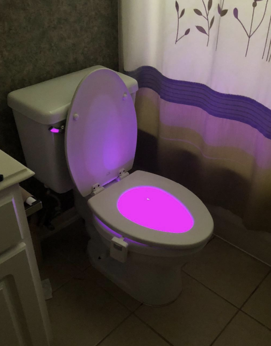 a photo from a reviewer showing their toilet illuminated by a pink light