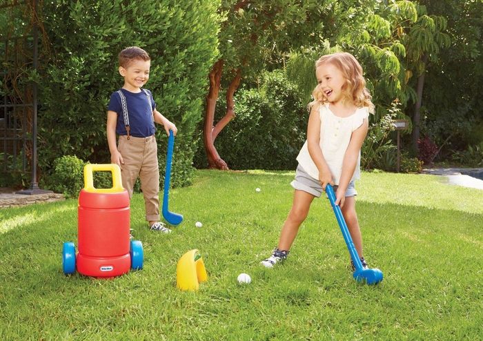 Children enjoying themselves while playing with the Little Tikes golf set, learning and having fun with the golf clubs and ball.