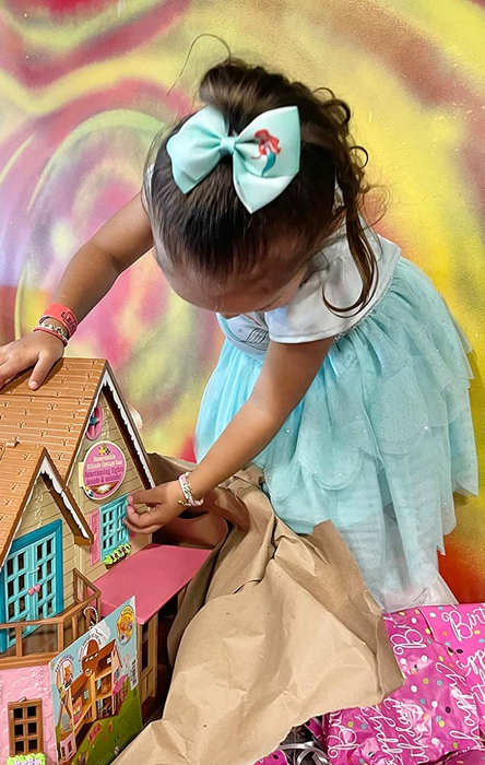 a child wearing a large light blue Ariel-themed hair bow