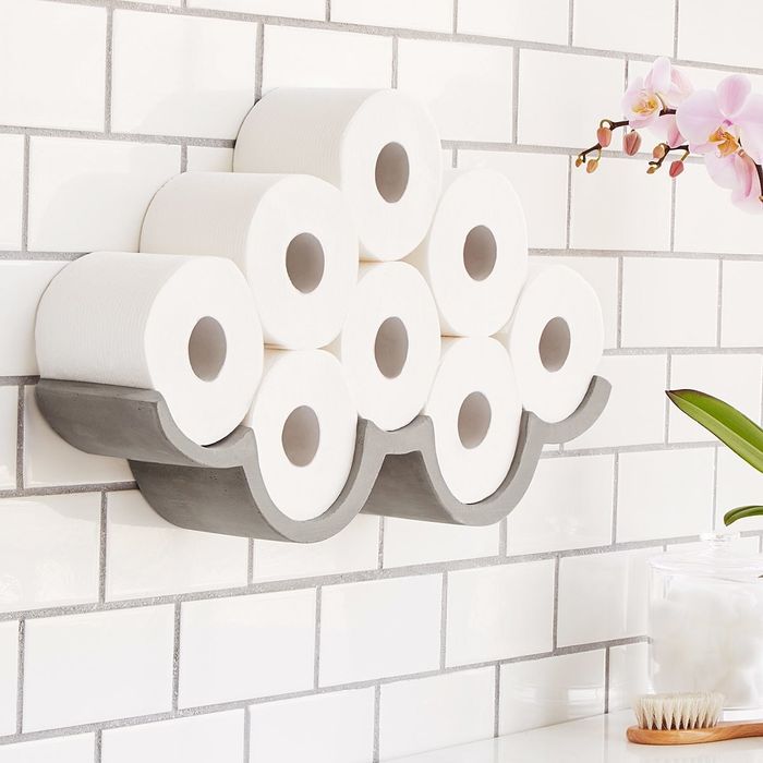 The holder mounted on a bathroom wall, displaying rolls of toilet paper in a whimsical cloud design