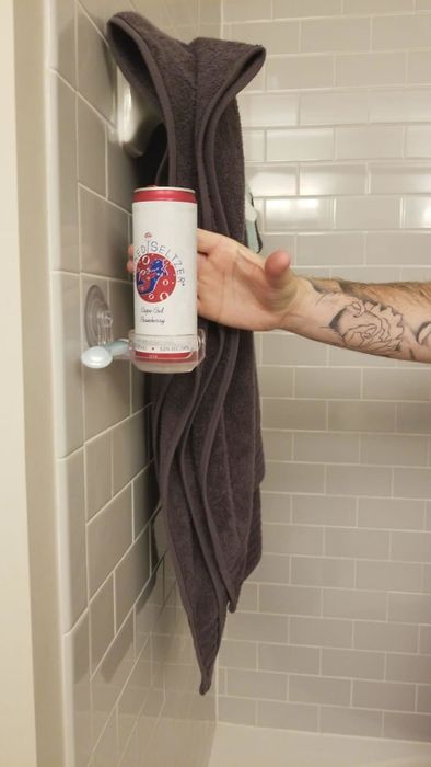 A reviewer is seen grabbing a beer from the conveniently placed drink holder while in the shower.