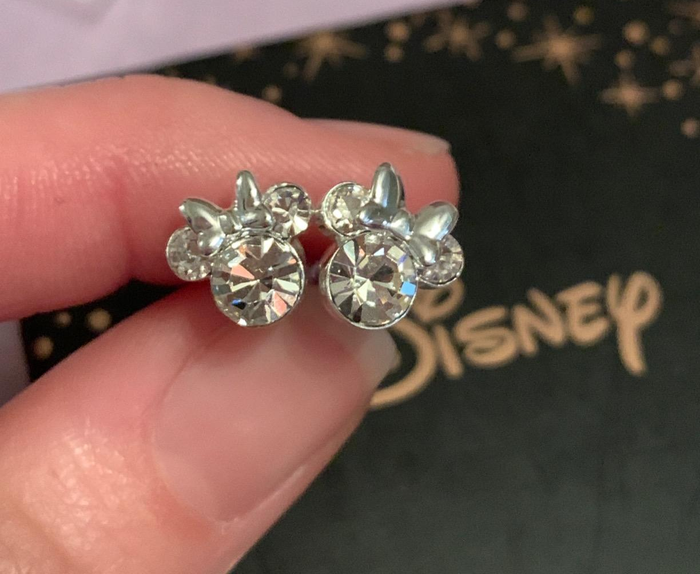 a reviewer holding a pair of Minnie Mouse-shaped stud earrings