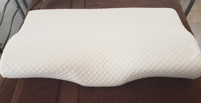 A rectangular memory foam pillow featuring a quilted, textured surface, displayed against a brown backdrop