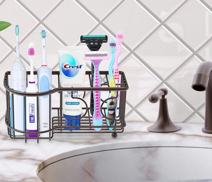 A wire toothbrush holder filled with toothbrushes, toothpaste, and razors neatly organized inside