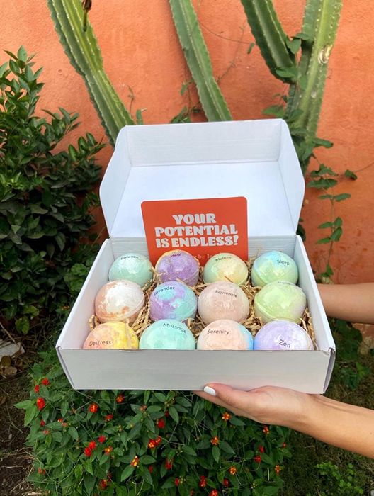 Hands holding a box filled with colorful, swirly-toned bath bombs