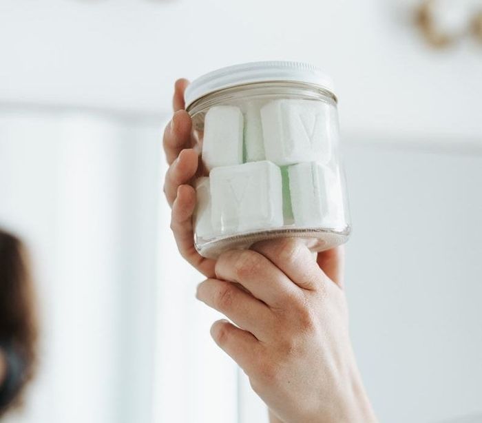 A photo of a hand holding a jar of toilet bath bombs.