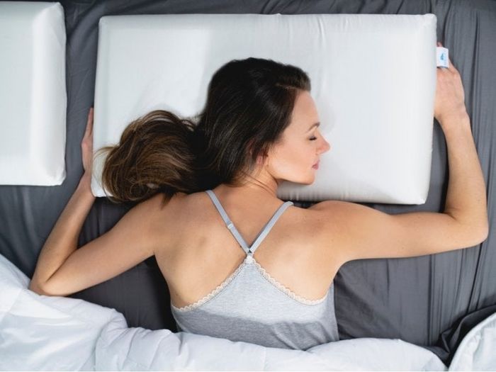model resting on their stomach with their head on a rectangular white pillow