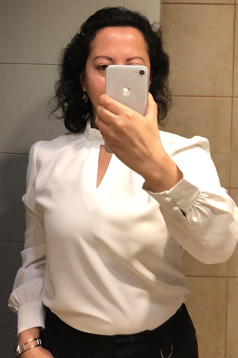Image of reviewer wearing a white long-sleeve blouse