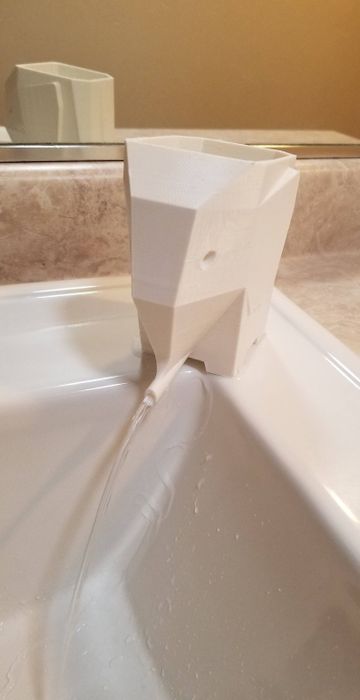 An elephant-themed toothbrush holder with water draining from its trunk