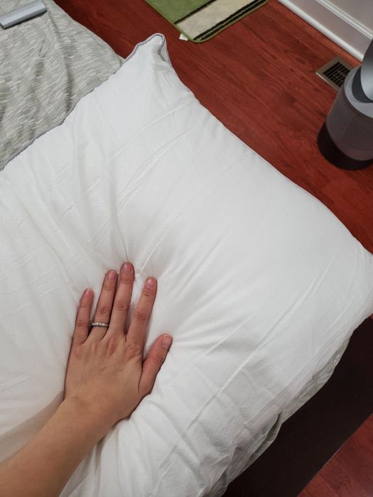 A detailed shot of a reviewer demonstrating the pillow's fullness by pressing into it