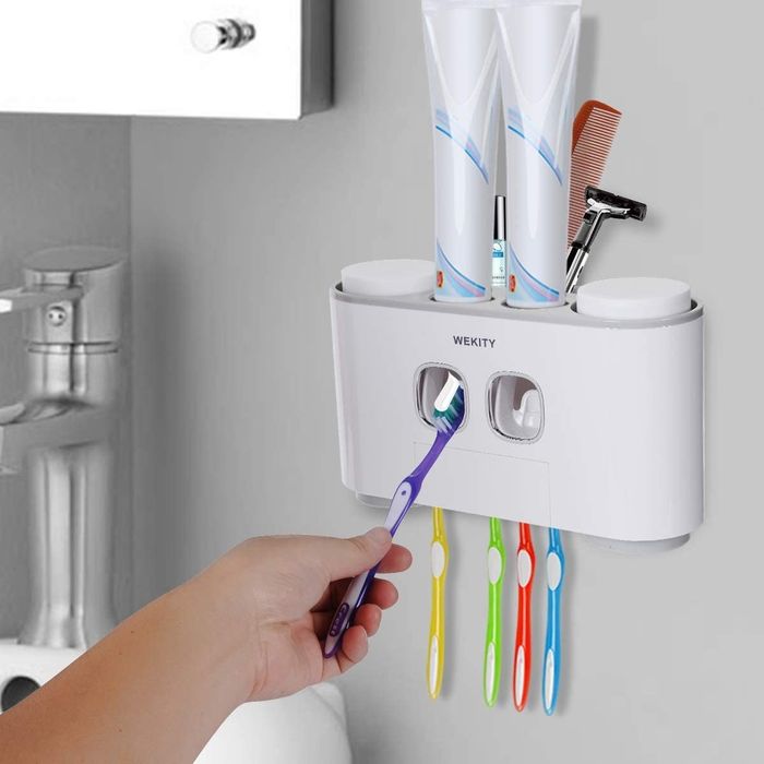 A model demonstrates how to use an automatic toothpaste dispenser by holding a toothbrush up to it.