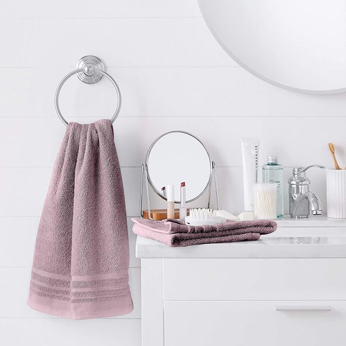 A hand towel in the shade Lavender Bloom draped over a towel hook in a bathroom.