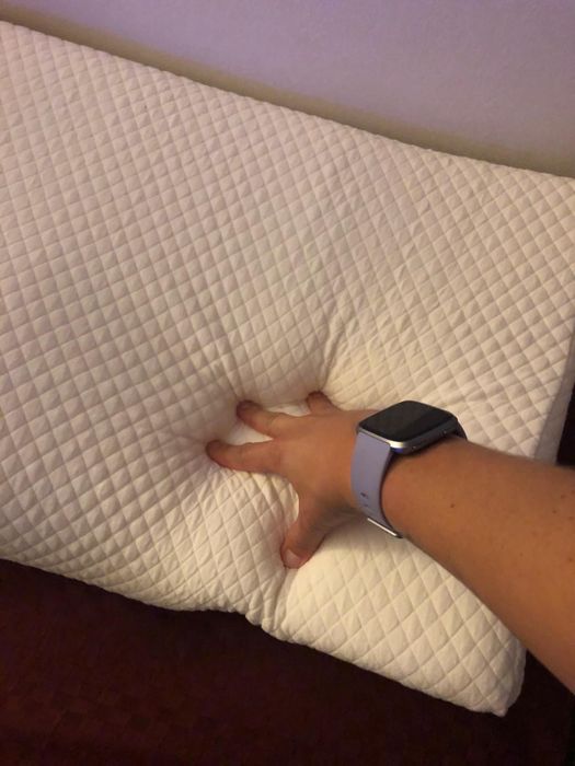 a hand pressing into the memory foam of the pillow