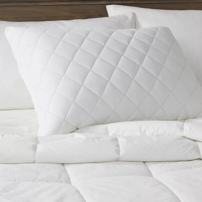 A white quilted pillow on a bed, highlighting a stylish addition to home bedding
