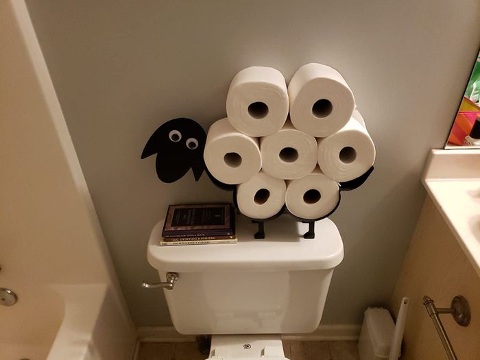 The same sheep-shaped toilet paper holder sitting atop a white toilet, adding charm to the bathroom.