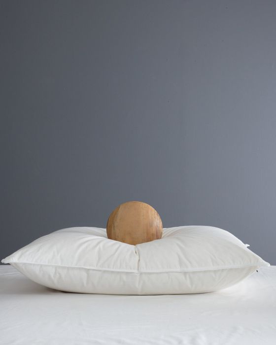 A circular wooden item placed on a soft white pillow