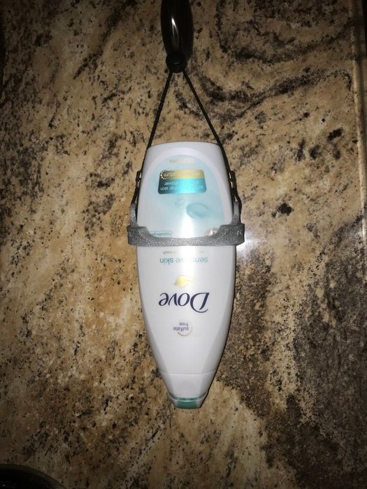 A bottle of body wash positioned upside down in its holder.