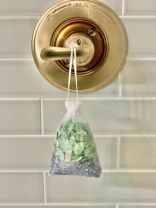 A small pouch filled with lavender and eucalyptus, elegantly hanging from a bath handle