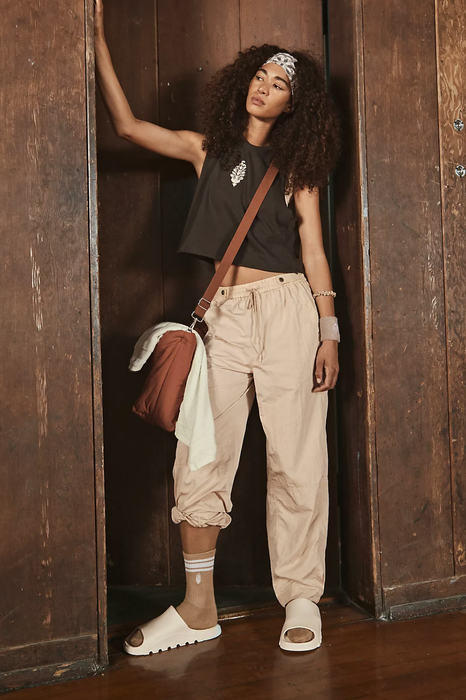 A photo of the model wearing the windbreaker pants in a cream color.