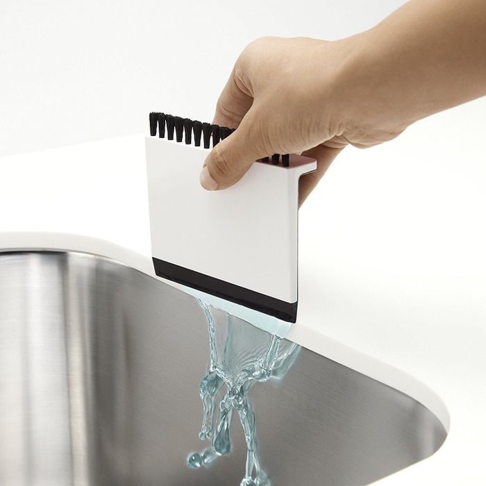 A hand using the squeegee side to push water into the sink