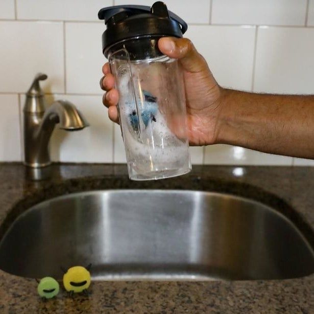 Hands shaking a bottle containing one of the cleaning sponges