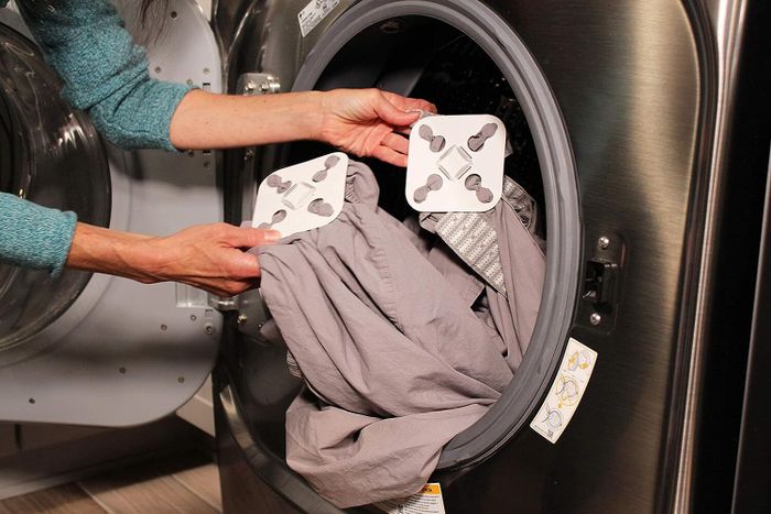 An individual placing laundry and a drying accessory into a front-loading washing machine