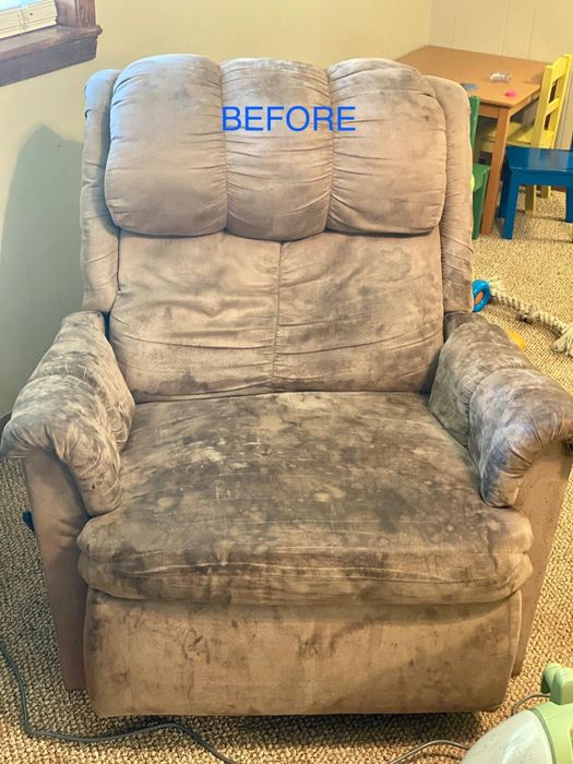 a tan-colored suede recliner with dark black stains scattered across its surface