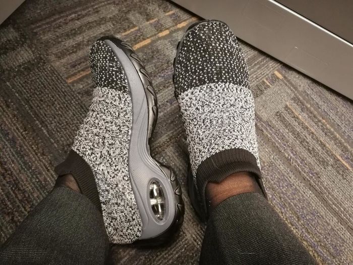 A reviewer wearing sock-sneakers in a gray color