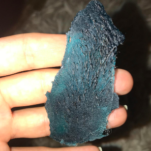 A reviewer displaying a used wax strip with a lot of removed hair on it